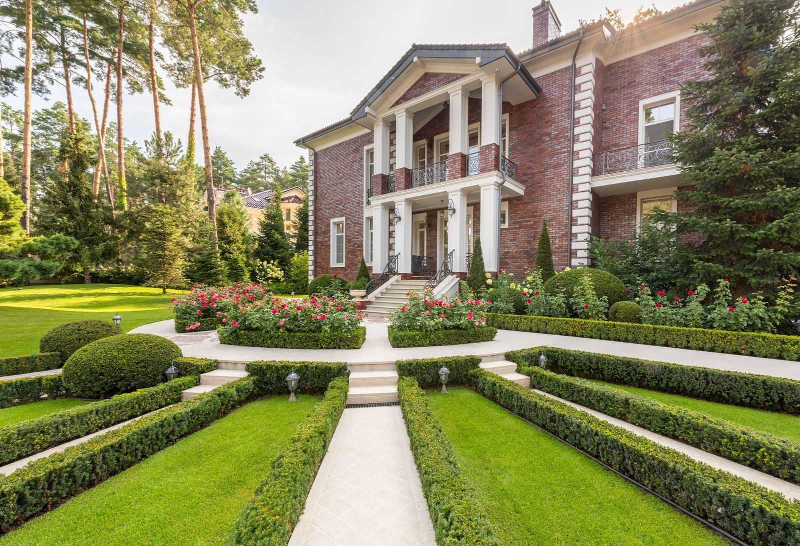 Modernes Haus mit grünem Rasen, Bepflanzung und Weg im Sommer