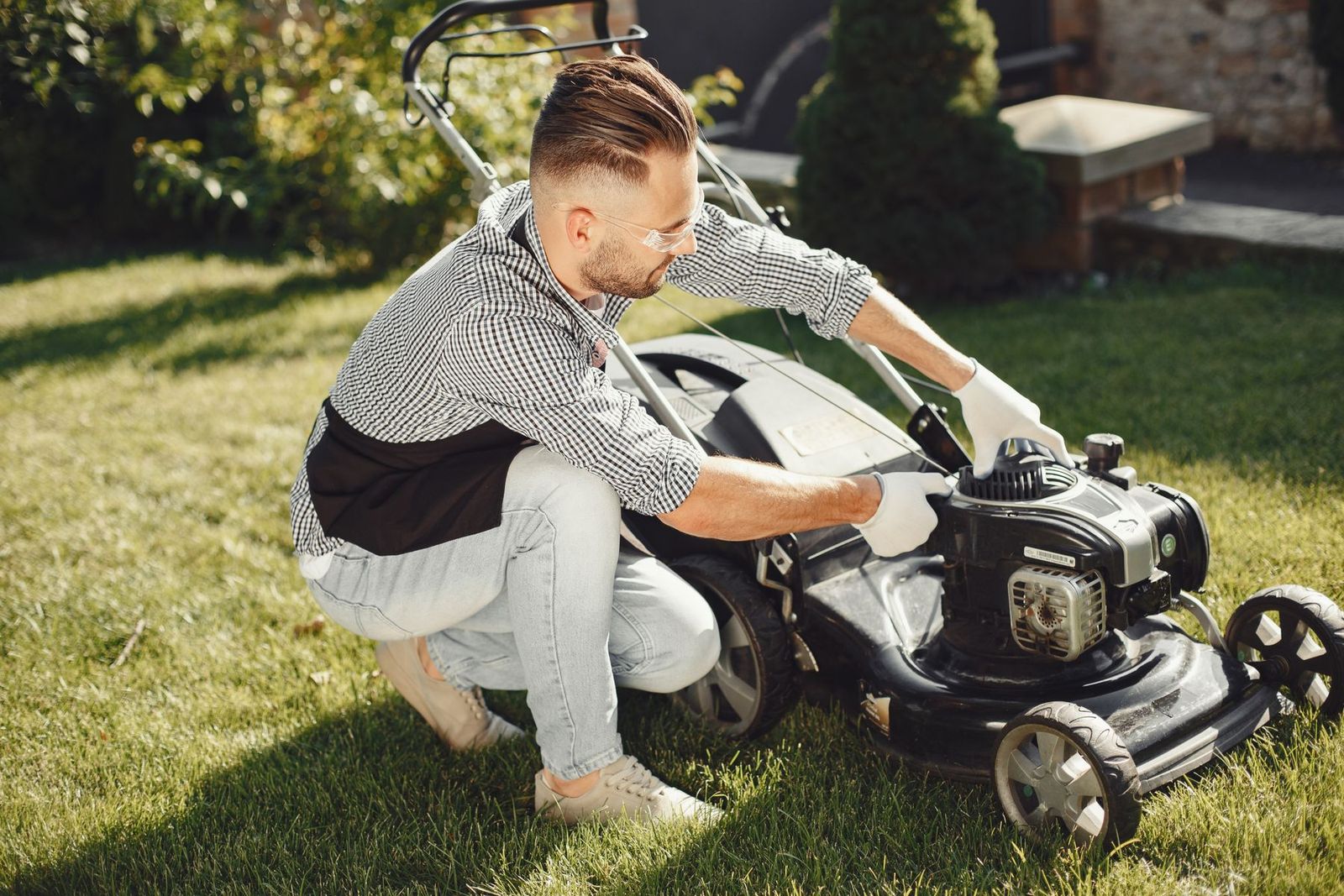 Mann bereitet den Rasenmäher für die Gartenarbeit vor